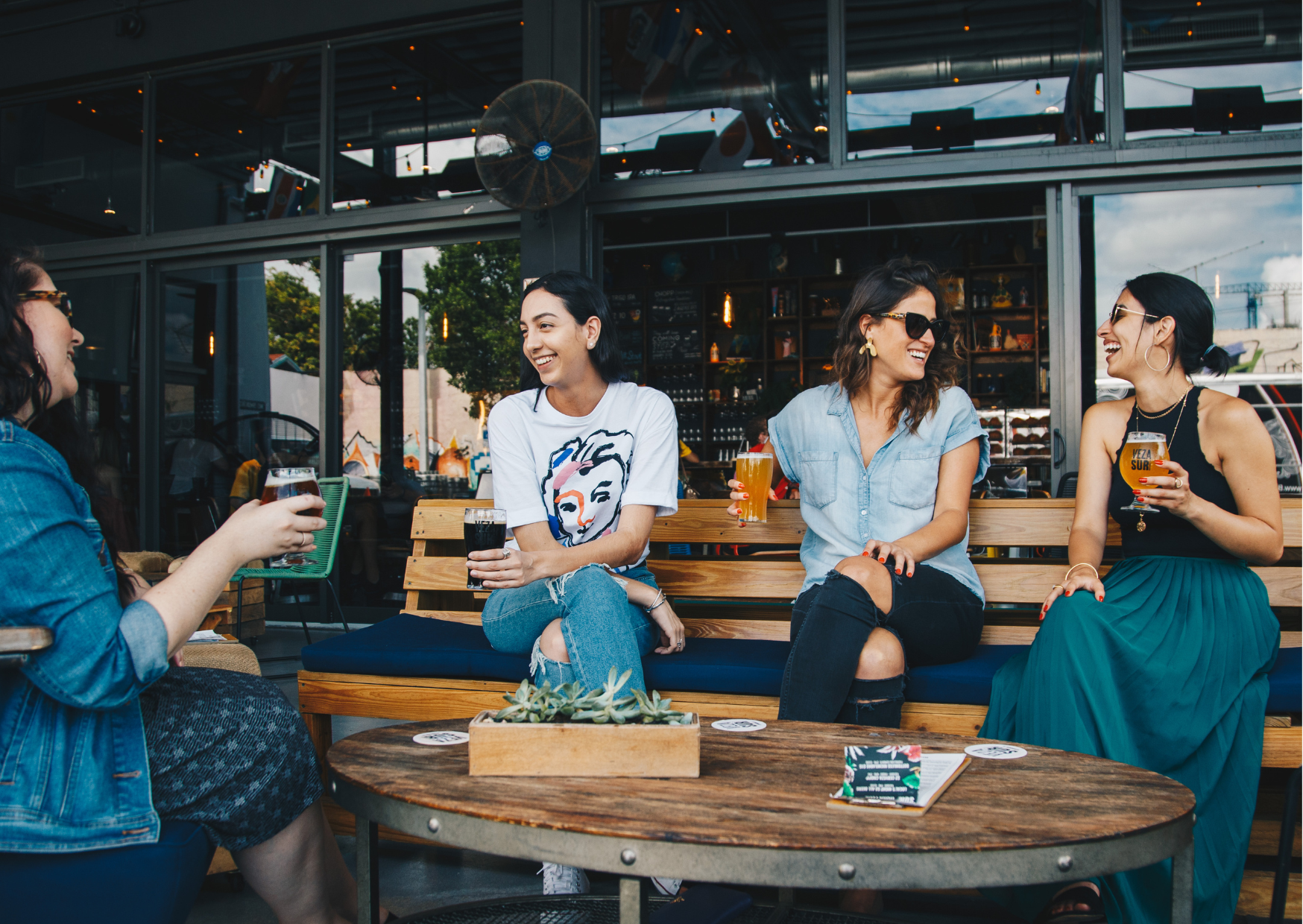 Donne che conversano sorridendo in un ambiente informale, simbolo di networking, scambio di idee e supporto reciproco all'interno di una community.