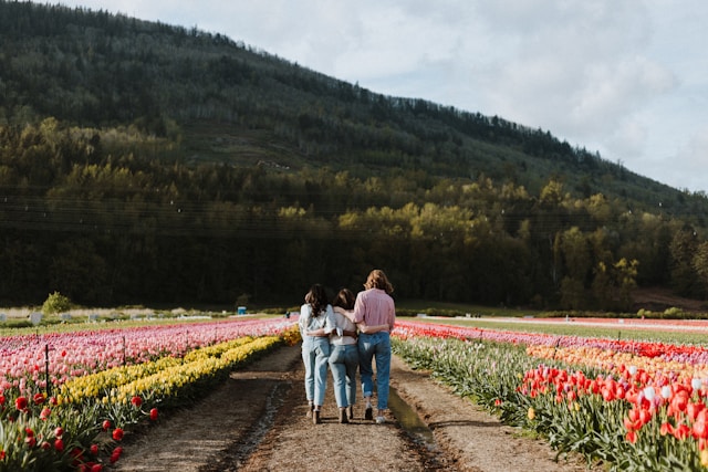 accettare una malattia cronica: tre donne di spalle passeggiano tra campi di fiori supportandosi a vicenda